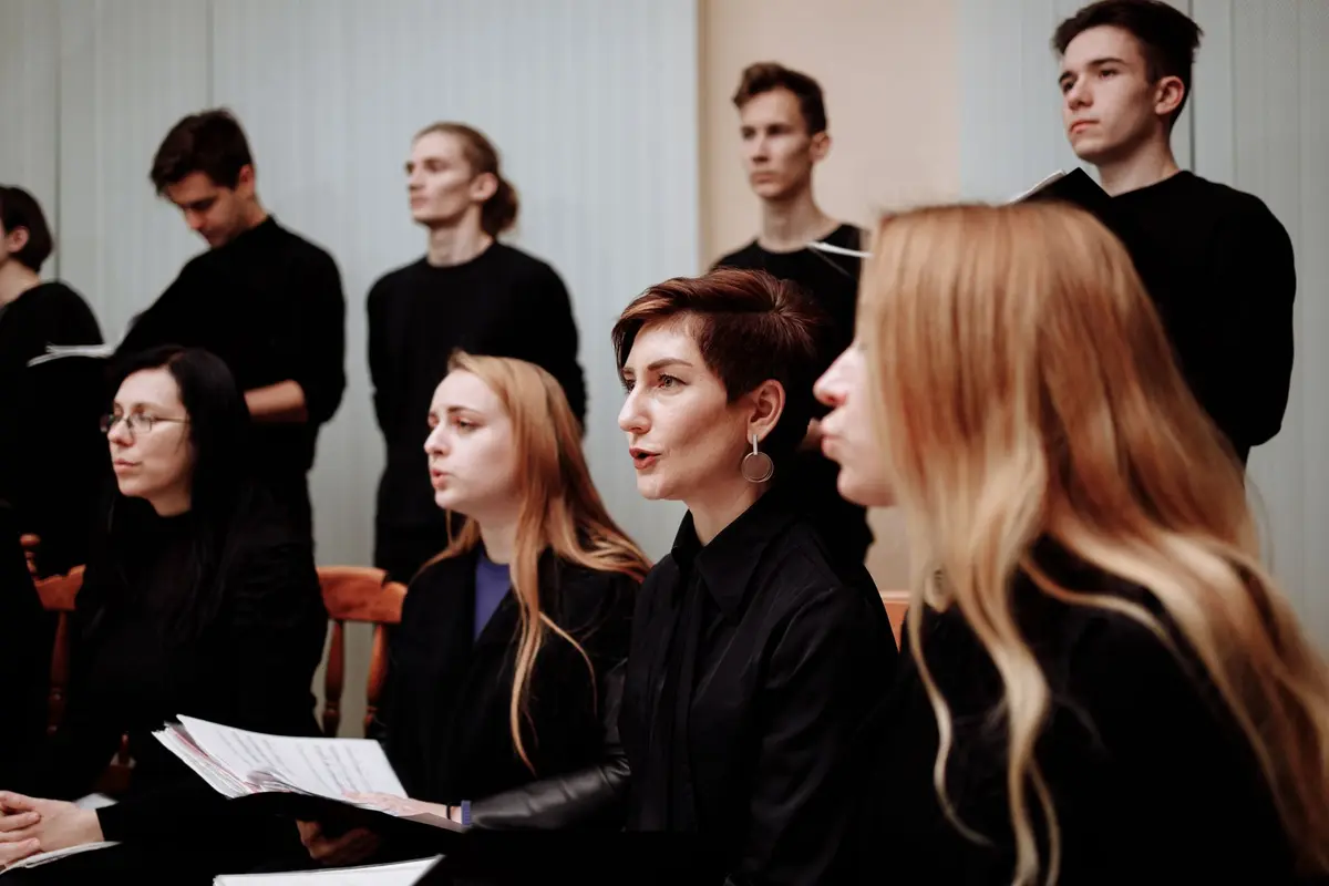 A choir dressed all in black singing together while holding sheet music