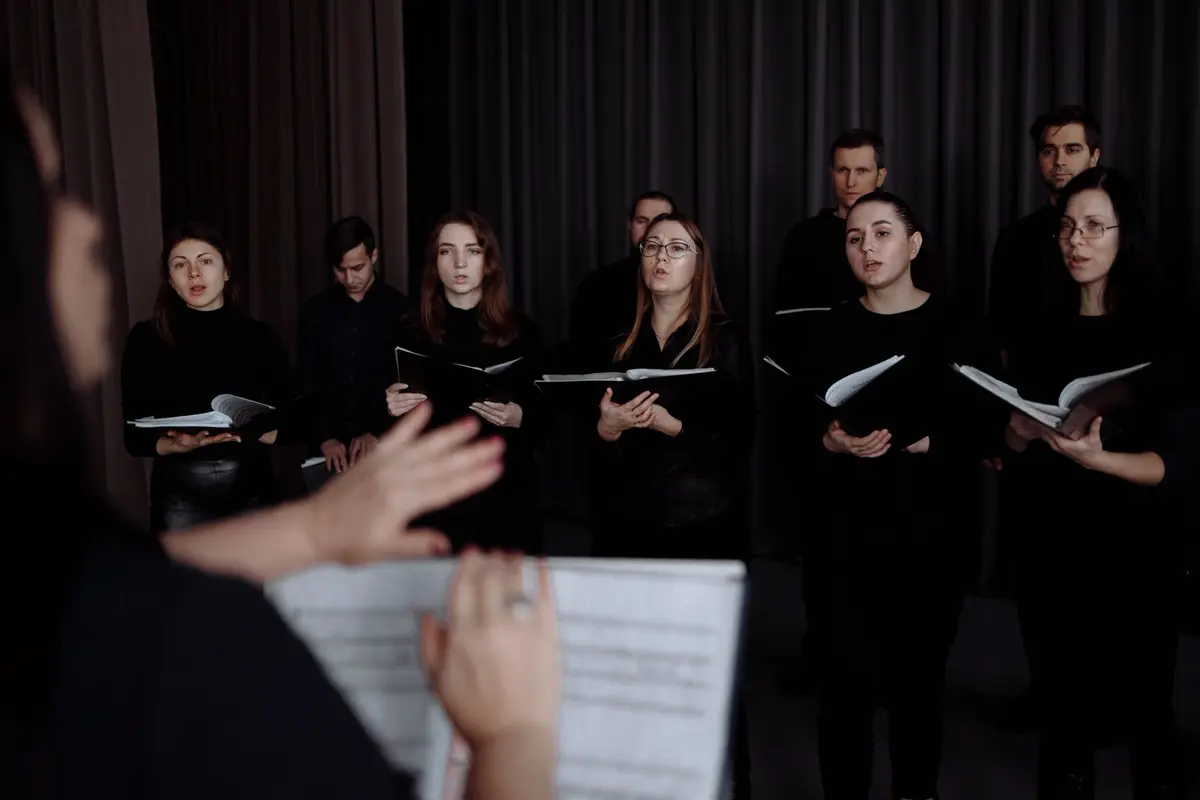 A choir rehearsing with music folders while a director leads them
