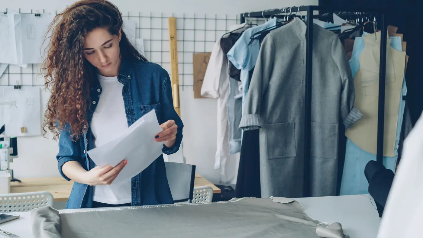 A designer reviewing garment sketches and church t-shirt design ideas in a studio