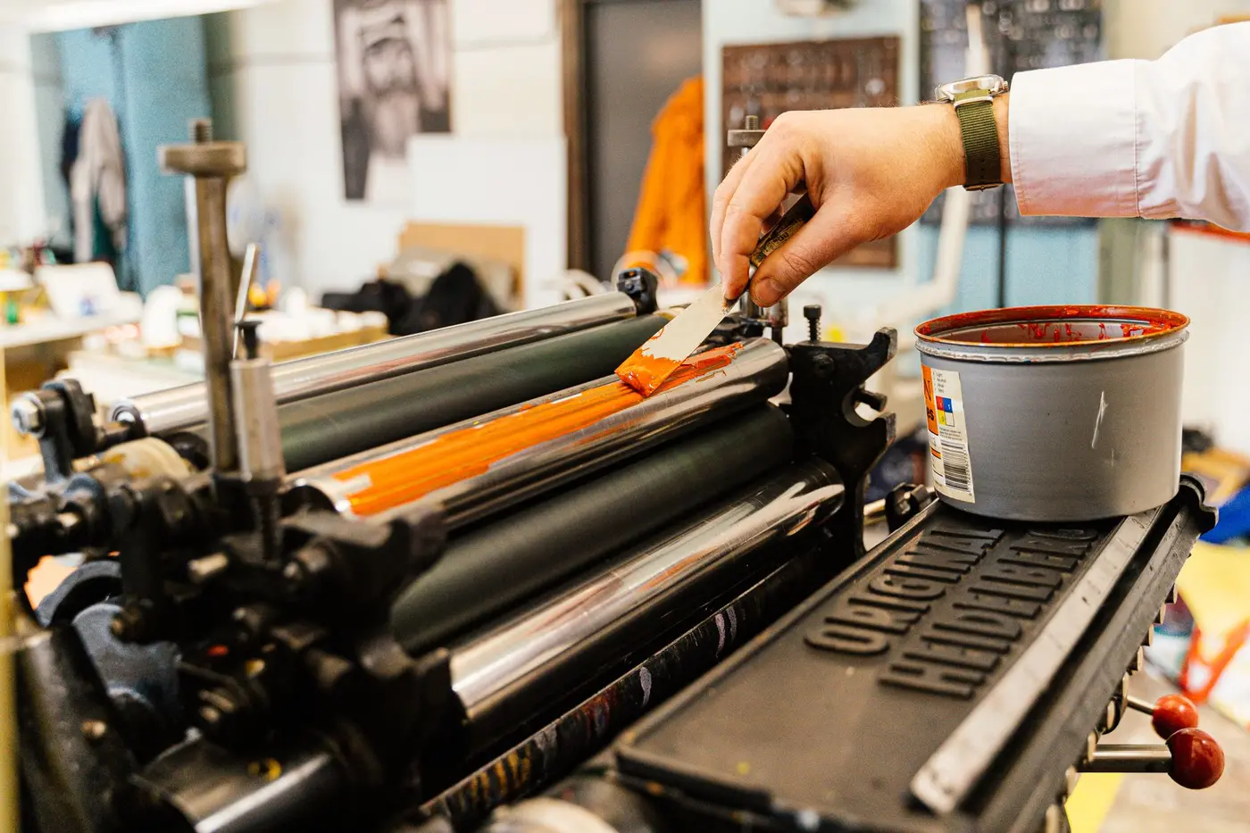 A screen printing press applying bright orange ink to apparel
