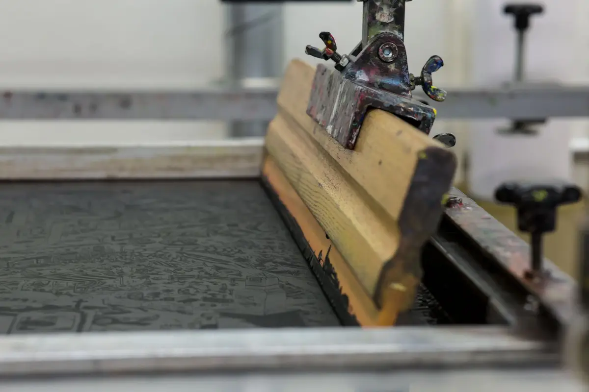 A screen printing press with a squeegee in a print shop