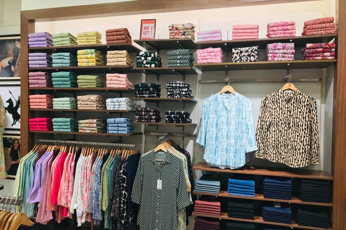 Neatly organized shirts and folded apparel on shelves in a retail store