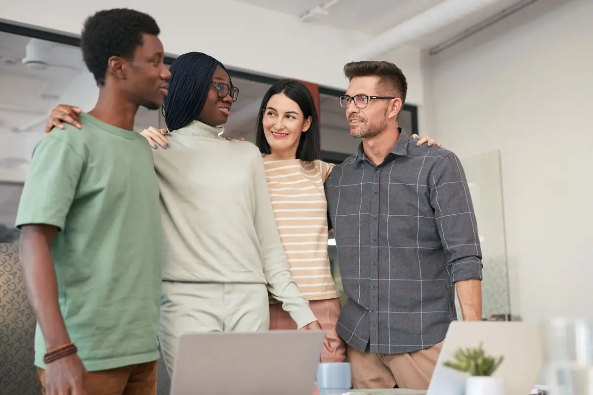 Four colleagues standing together and smiling in an office
