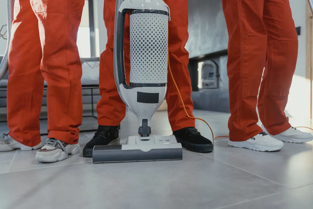 A cleaning team in matching uniforms working with a commercial vacuum