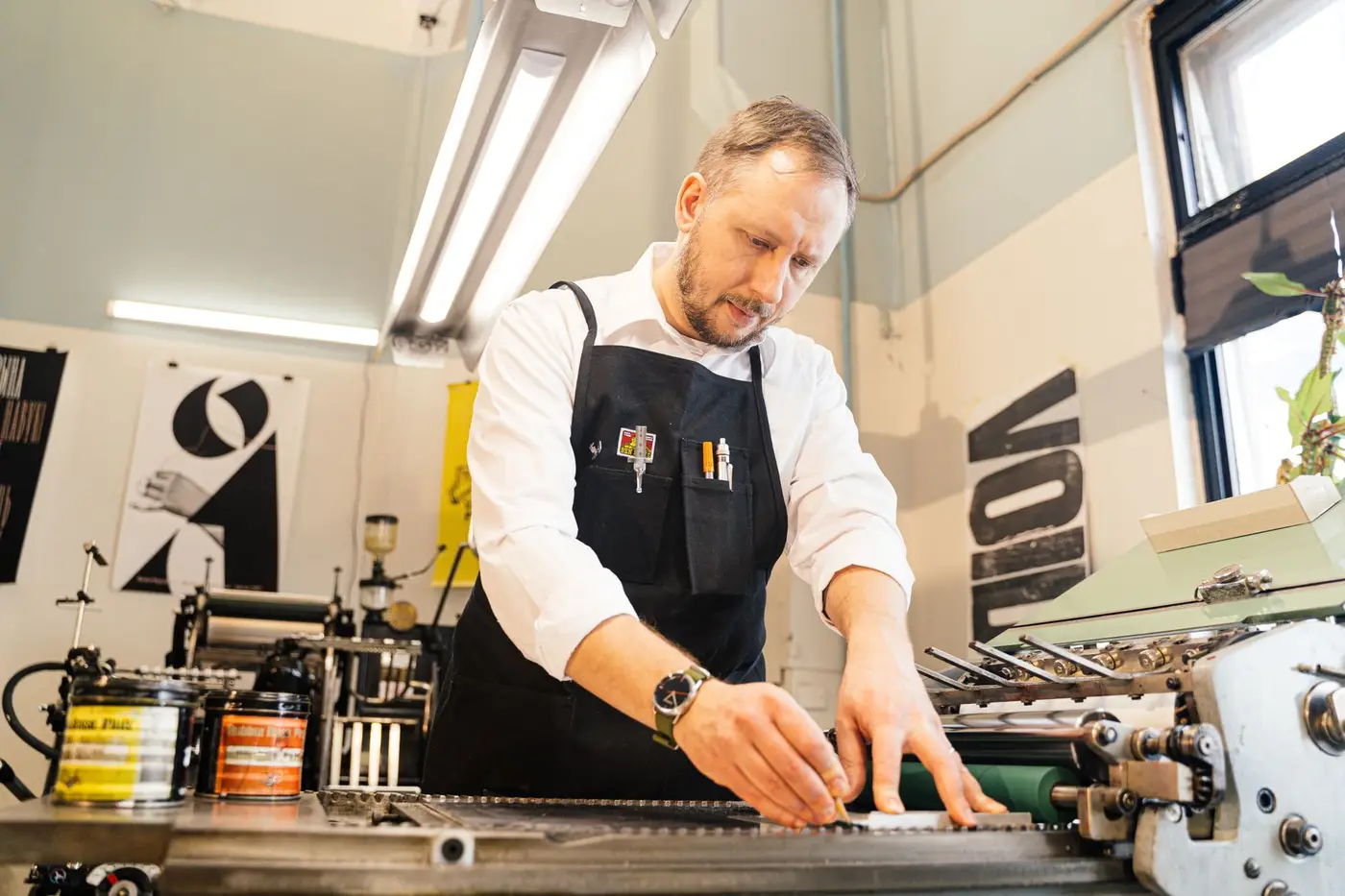 A craftsman working at a printing bench in a bright studio