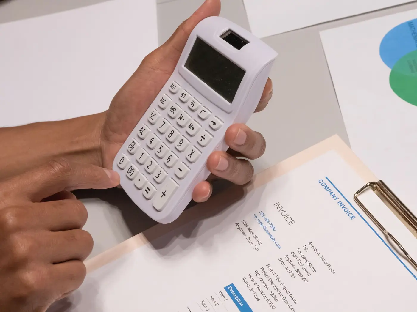 Hands using a calculator beside a printed invoice