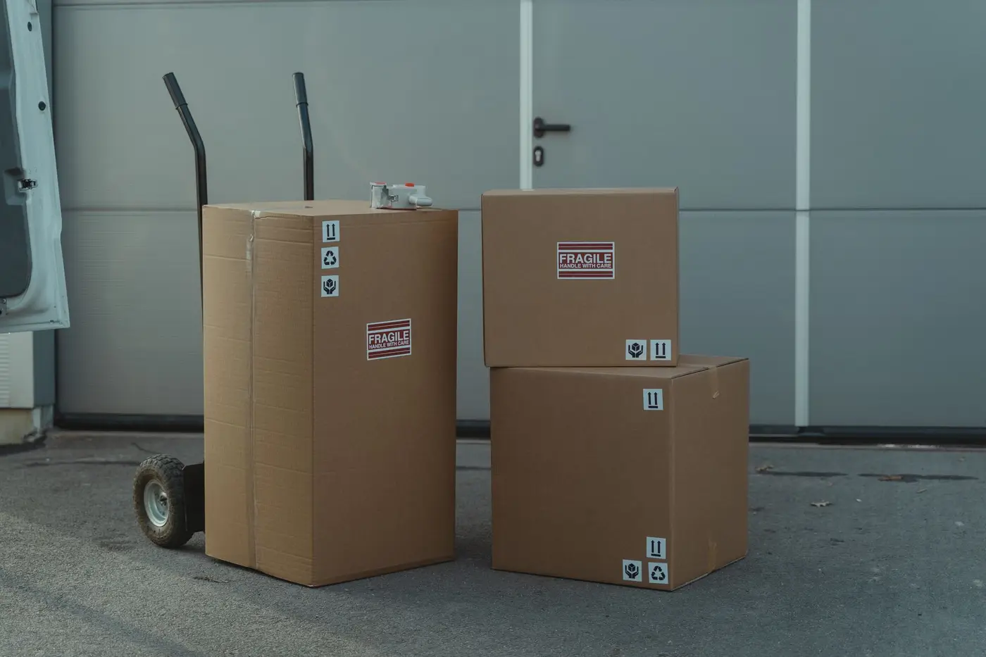 Cardboard shipping boxes stacked on a dolly outside a warehouse