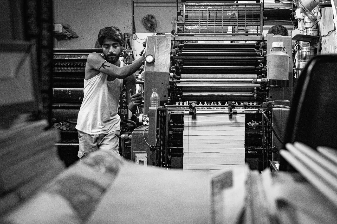 A worker operating a printing press, in black and white