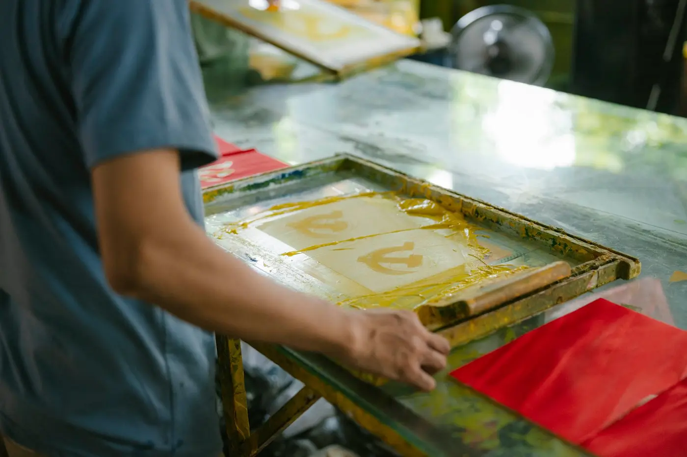 A printer working at a screen printing station in a workshop