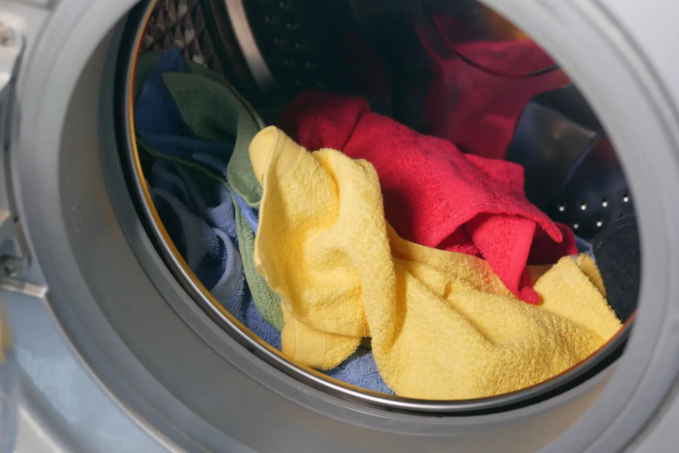 Colorful clothing tumbling inside a washing machine drum