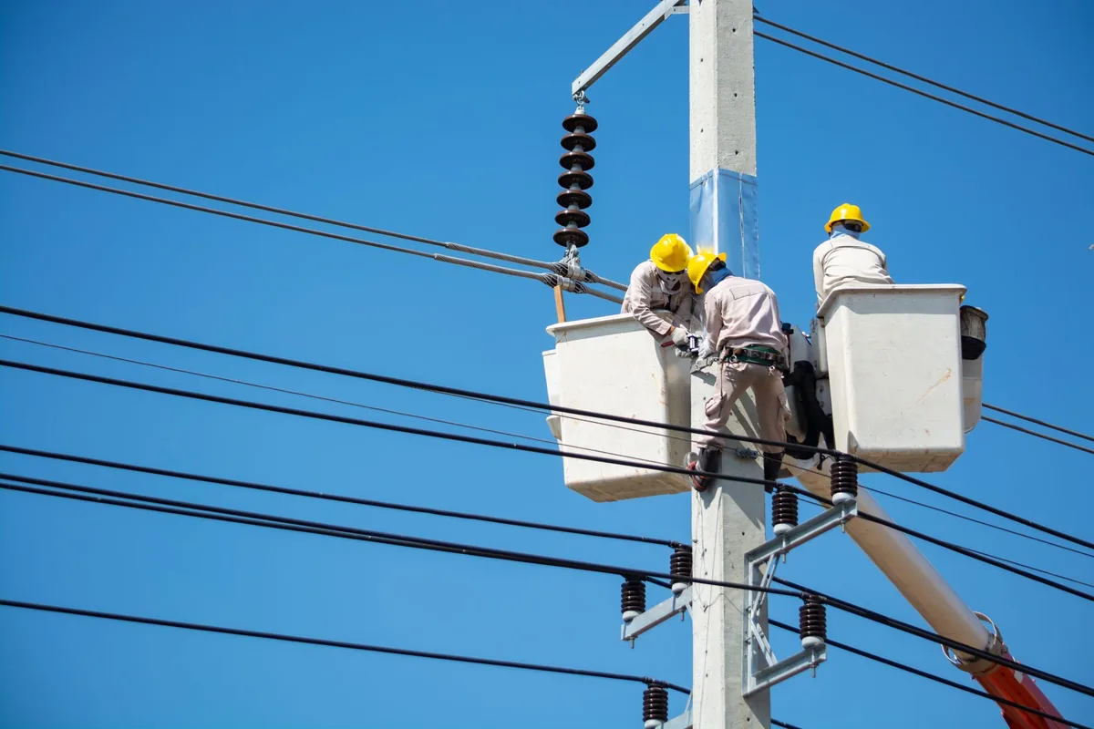 A crew in high-visibility safety gear working on overhead power lines