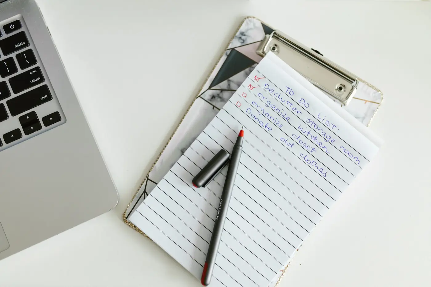 A to-do list on a clipboard beside a laptop and pen