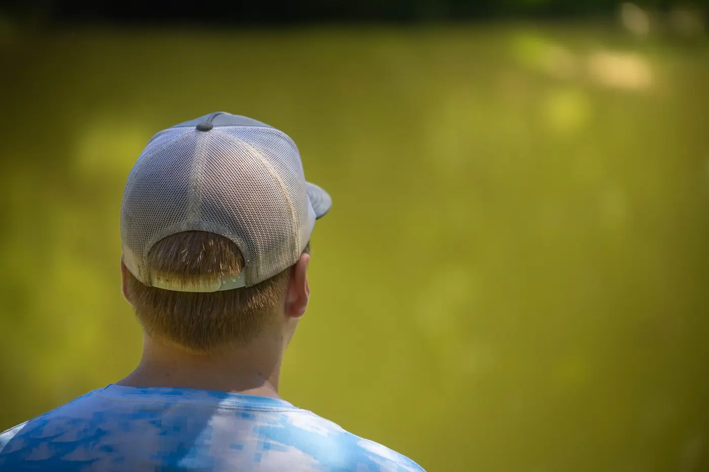 Back view of a person wearing a mesh-back trucker cap outdoors