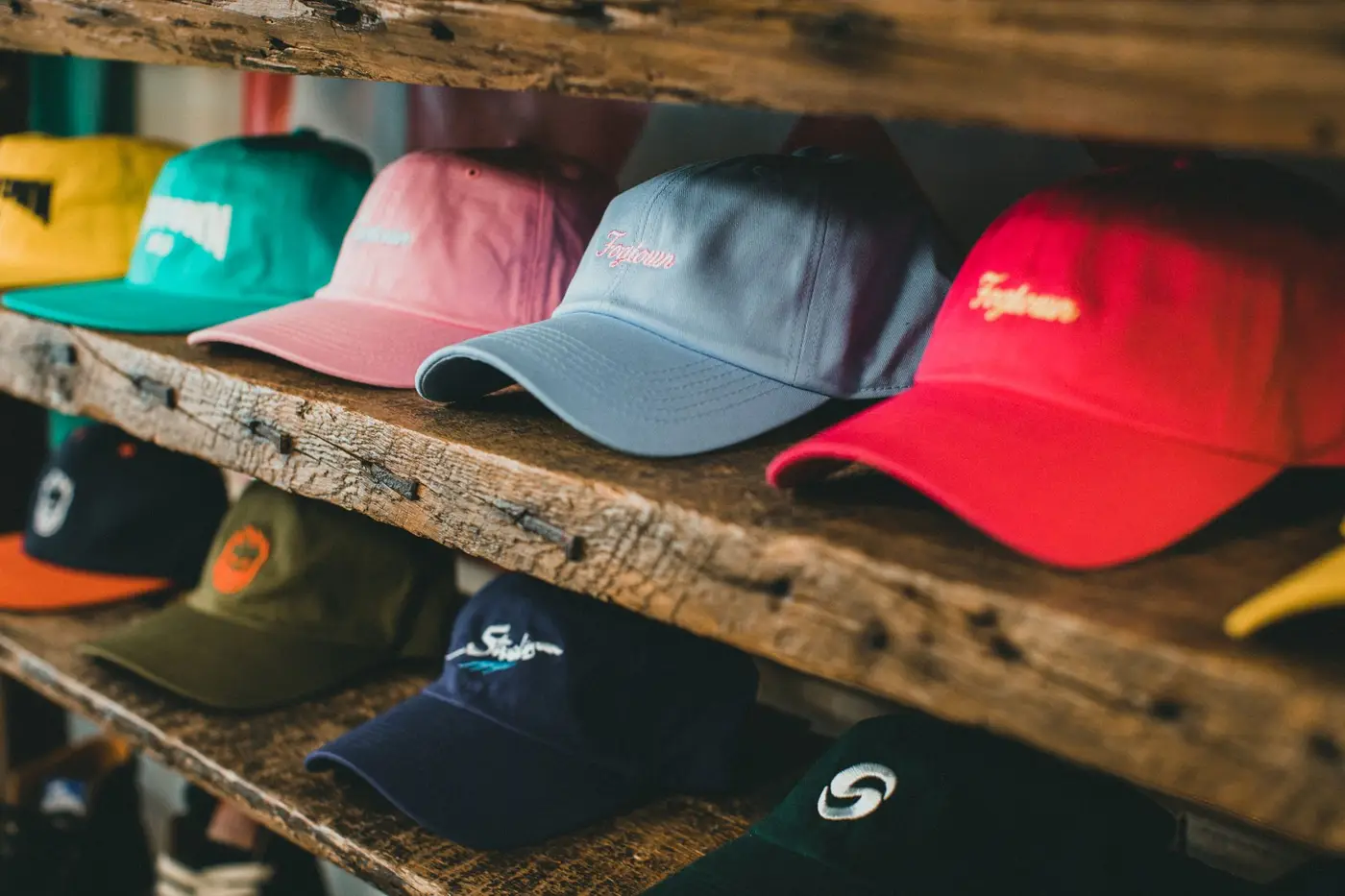Colorful embroidered baseball caps lined up on rustic wooden shelves