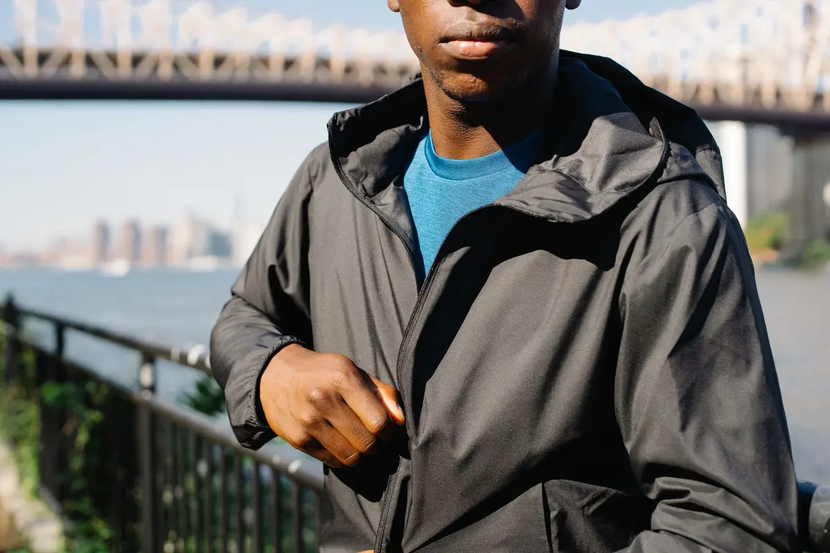 A man zipping up a performance jacket outdoors