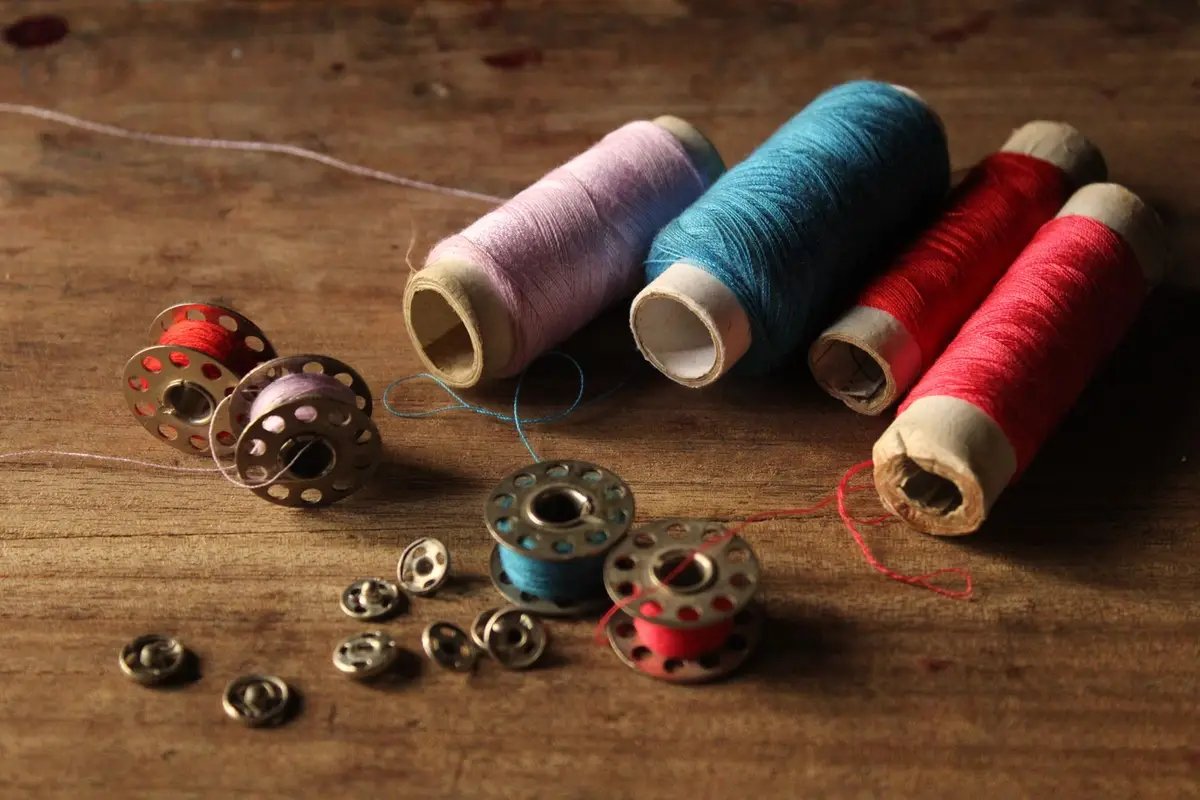 Spools of embroidery thread and bobbins on a wooden surface