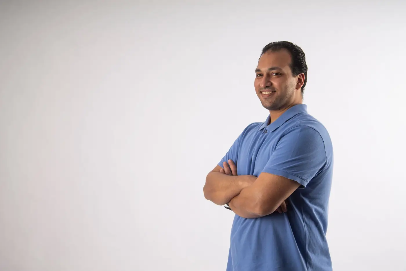 A man wearing a plain blue polo shirt against a light background
