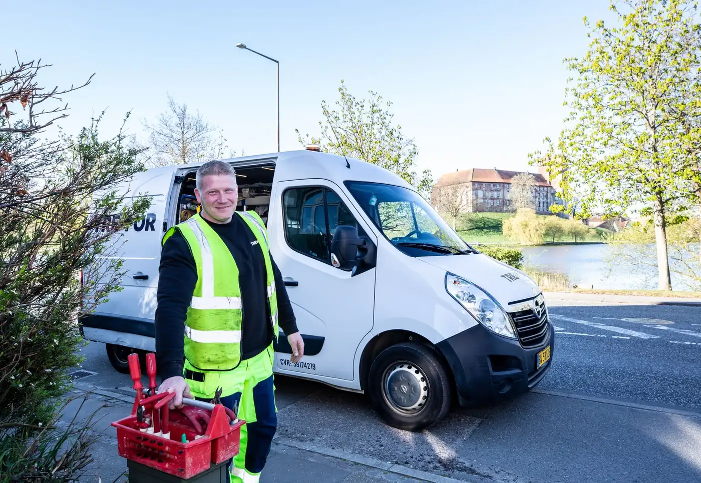 A worker in a high-visibility reflective vest standing beside a service van