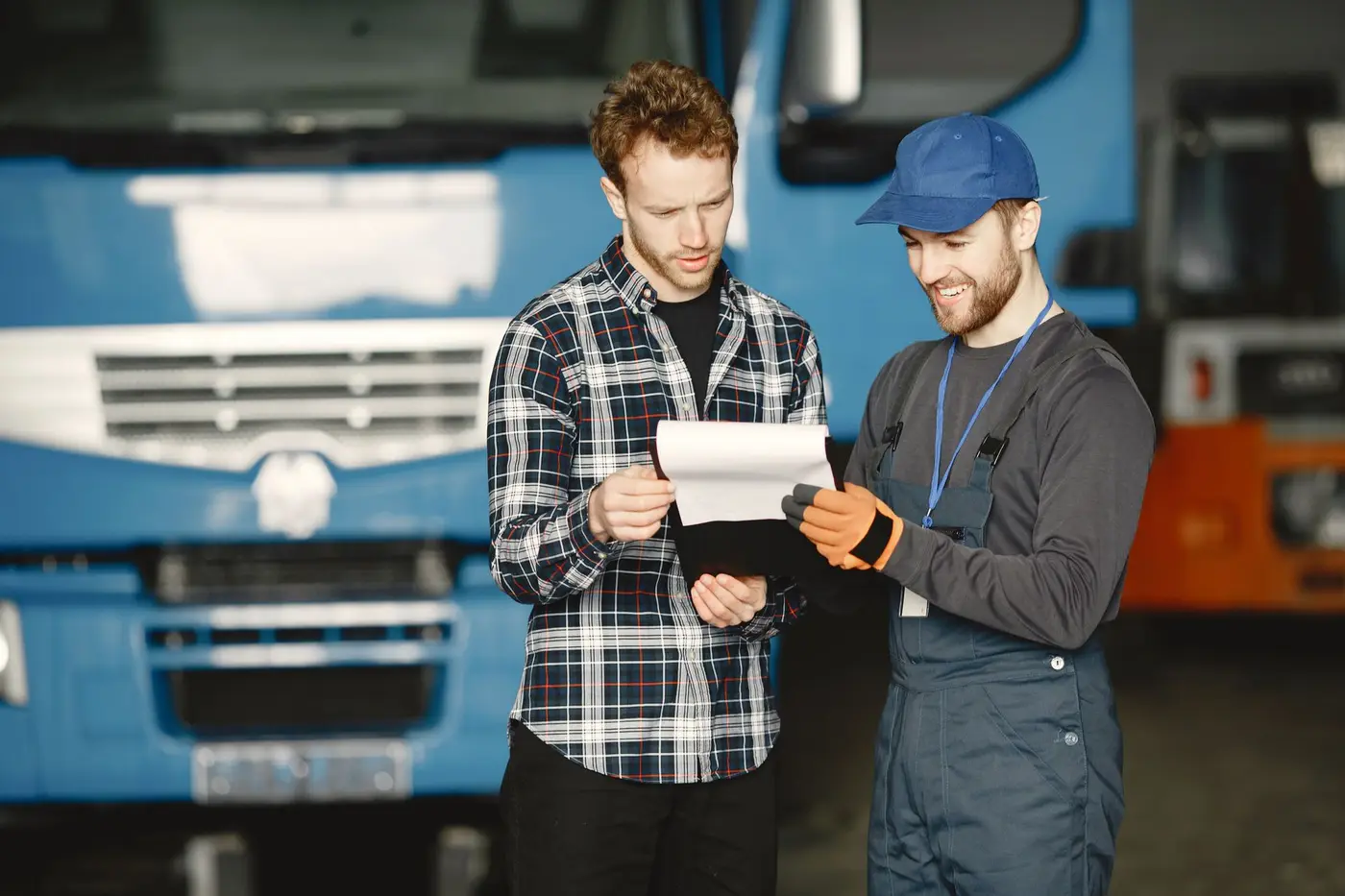 Two workers reviewing paperwork beside service trucks