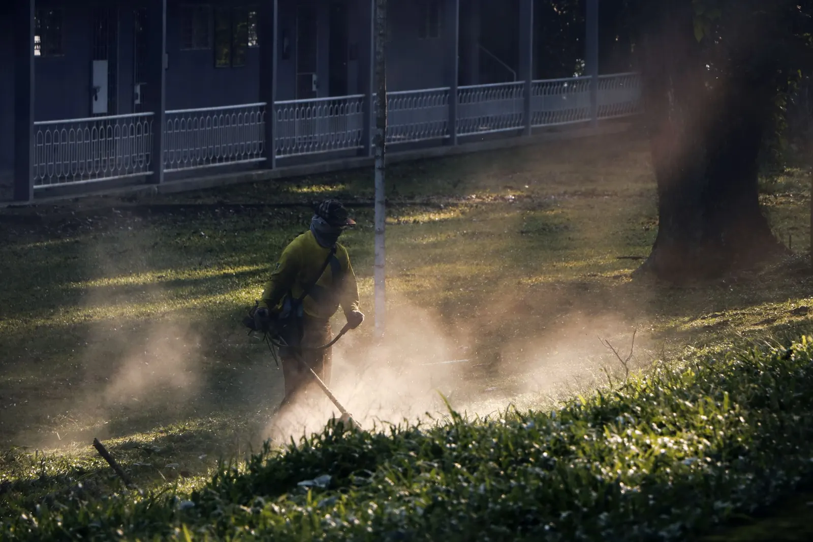 A landscaper cutting grass in a breathable work shirt