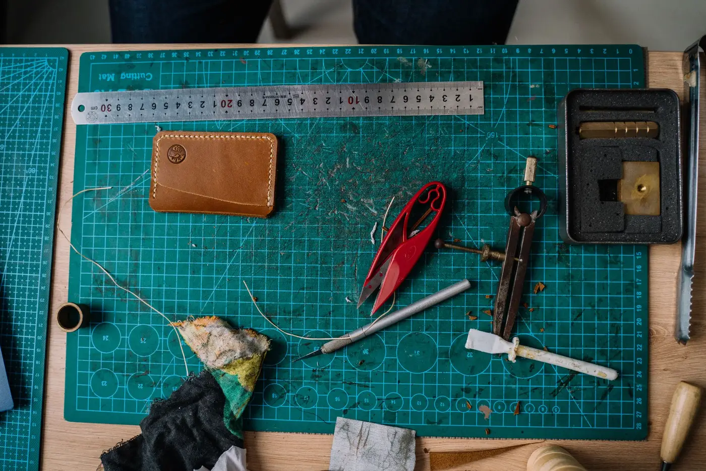 Leather working tools and a cutting mat on a workbench