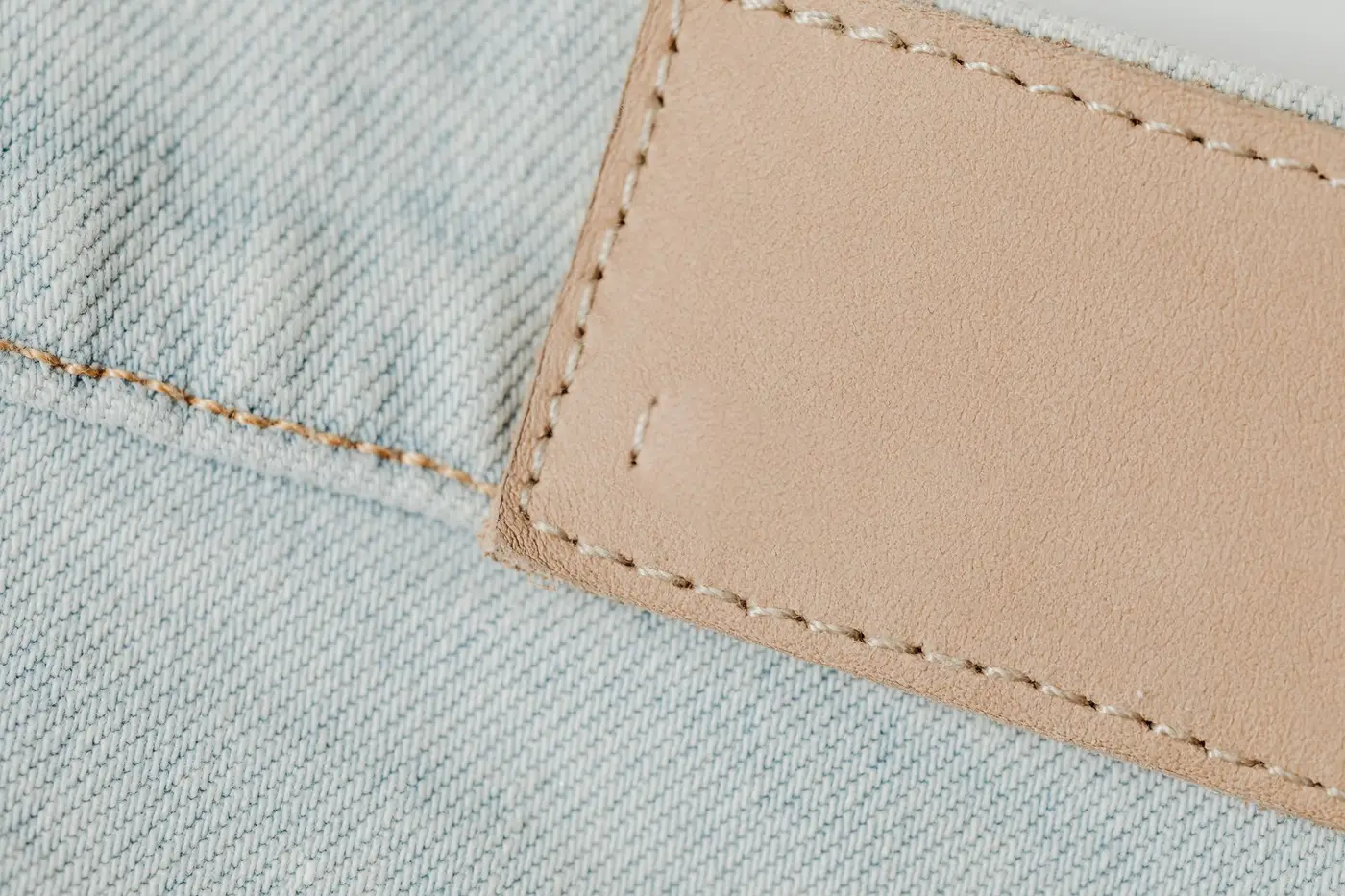A stitched leather patch on denim fabric, shown close up