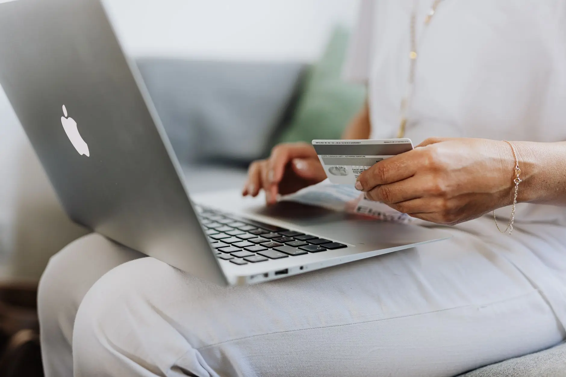 A person ordering branded gifts on a laptop with a card in hand
