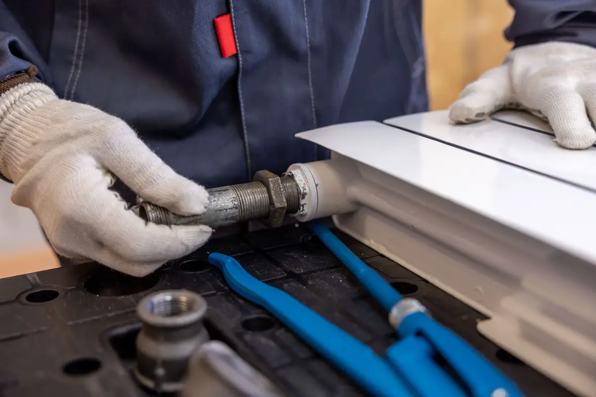 A plumber installing a radiator pipe with specialized tools
