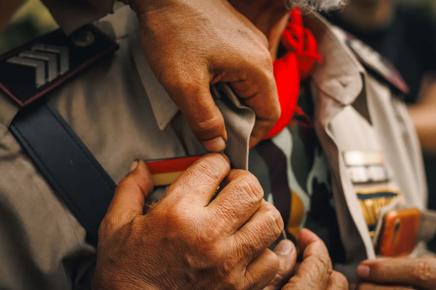 A person adjusting a uniform shirt with patches attached