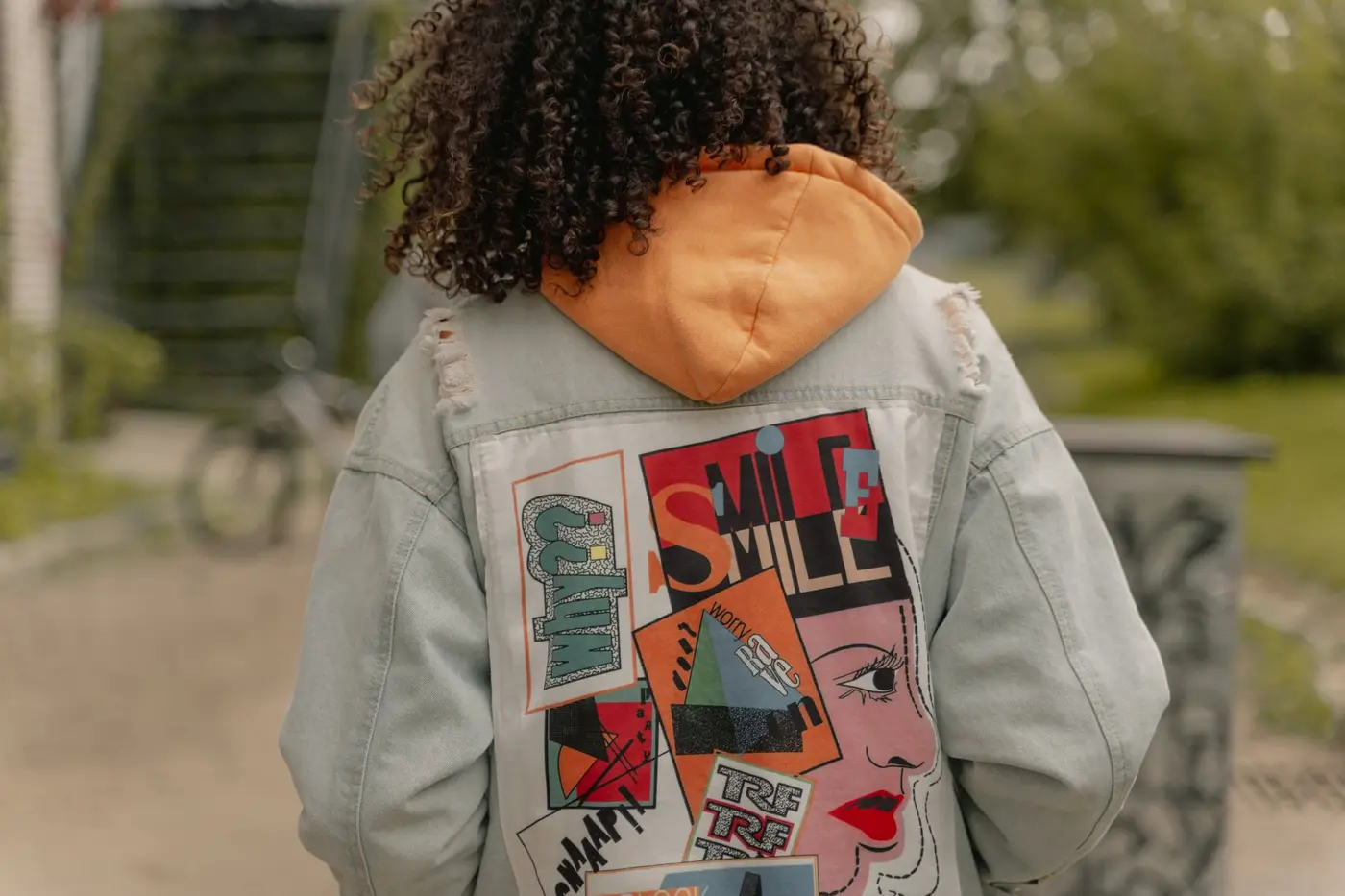 The back of a denim jacket covered in colorful patches