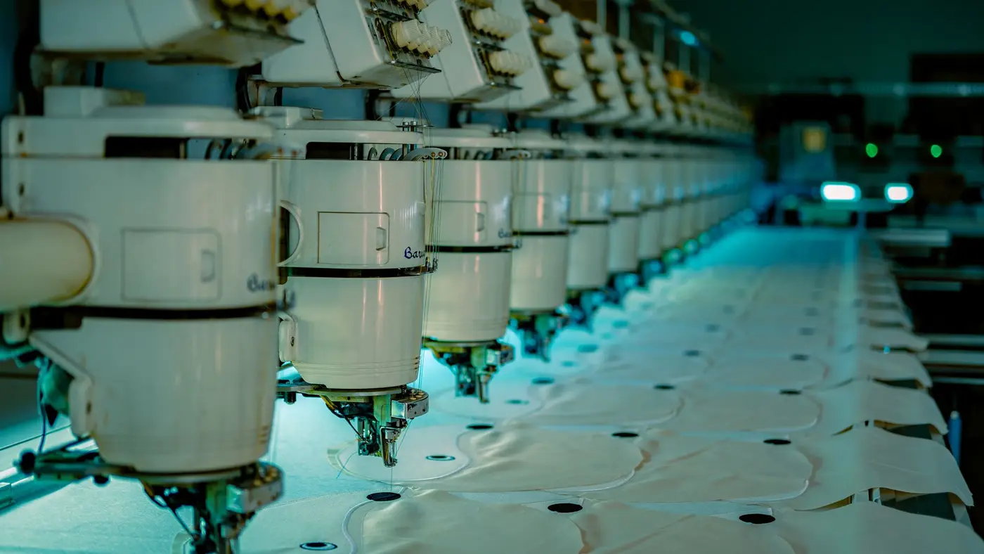 A row of industrial embroidery machines running in a factory