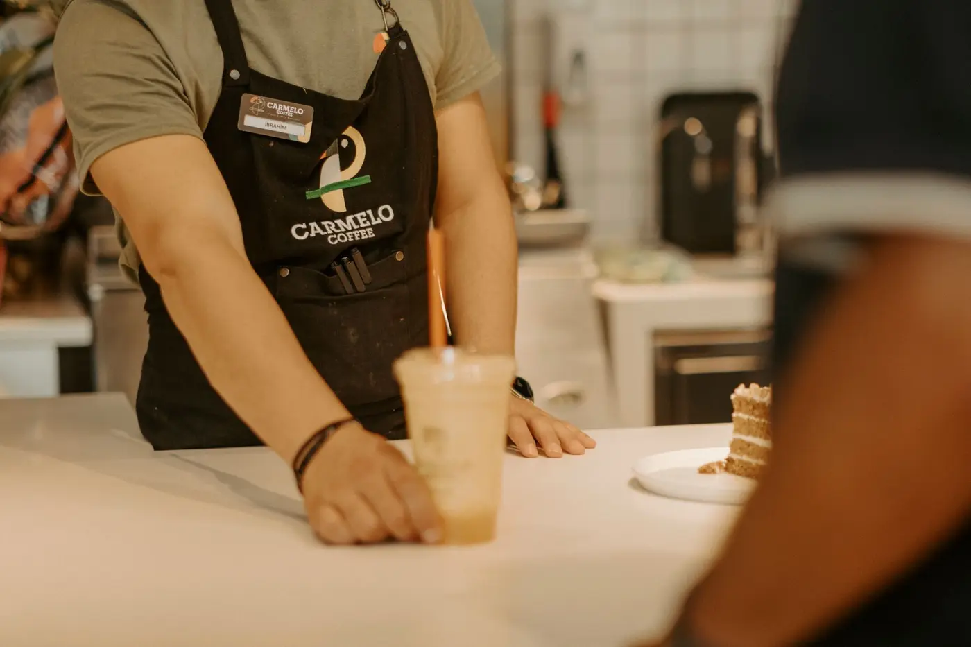 A restaurant staff member wearing a branded black apron with an embroidered logo