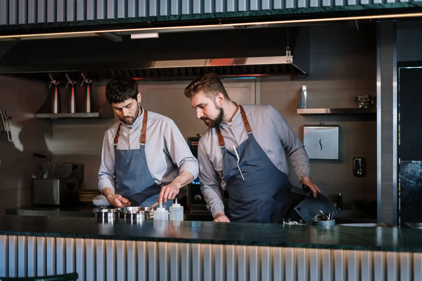 Two chefs in aprons working at a restaurant kitchen pass