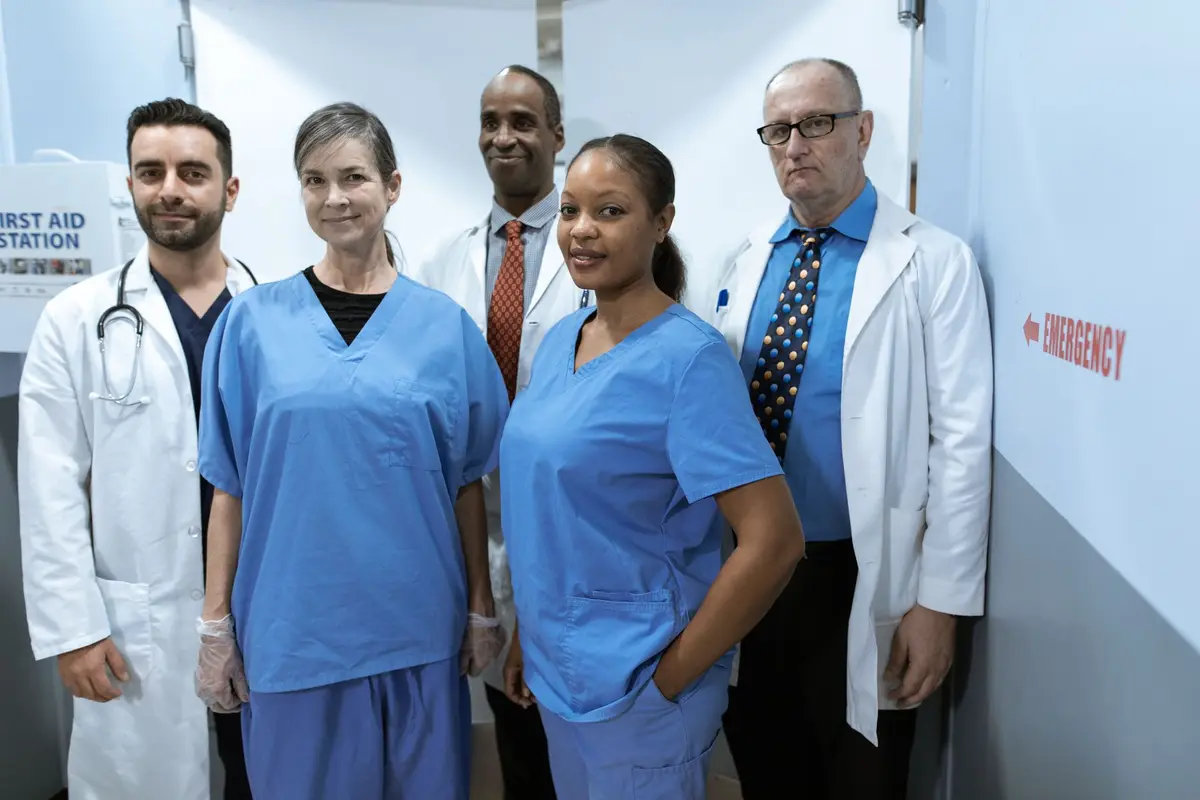 A healthcare team in matching embroidered scrubs and white coats at a clinic