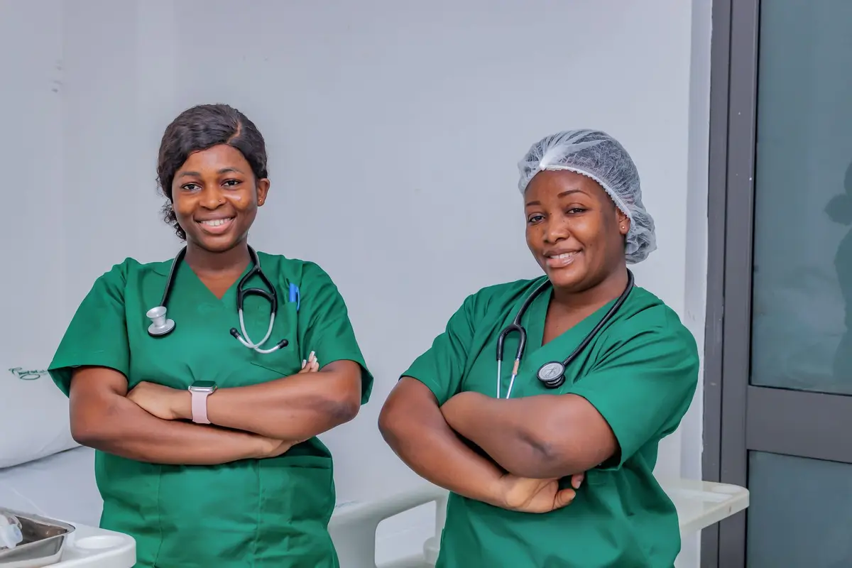 Two nurses in matching green embroidered scrubs at a clinic