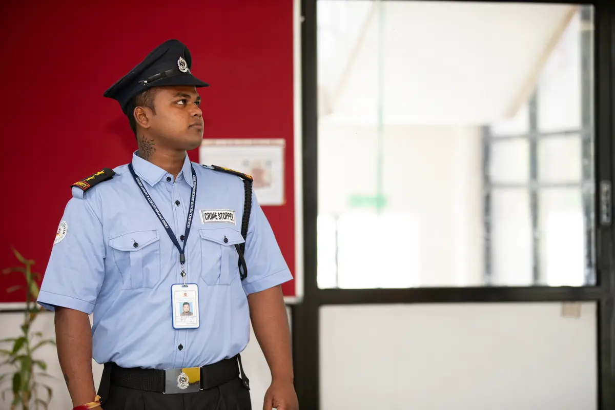 A security guard in a professional uniform standing at a building entrance