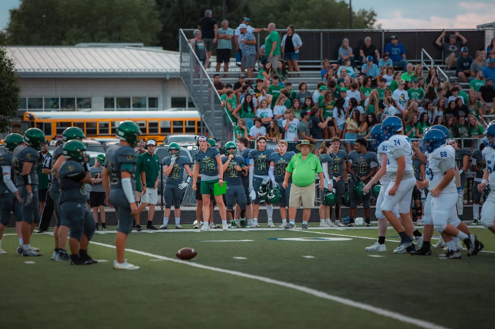 Students and fans cheering in school colors in the stands at a football game