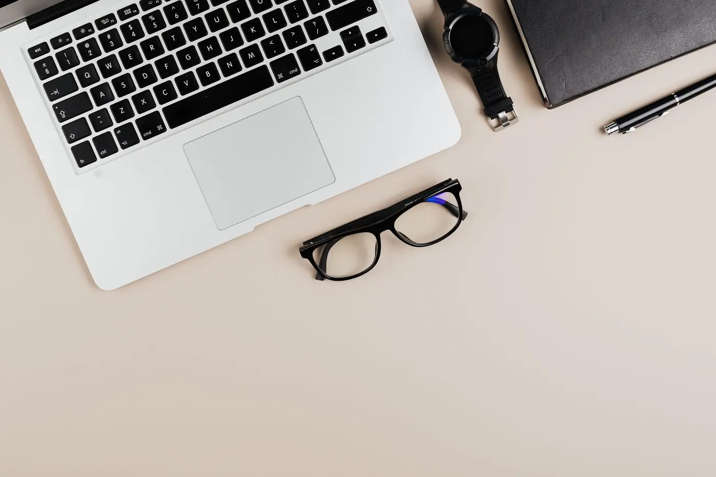 A flat lay of tech accessories, a laptop, and a notebook on a desk