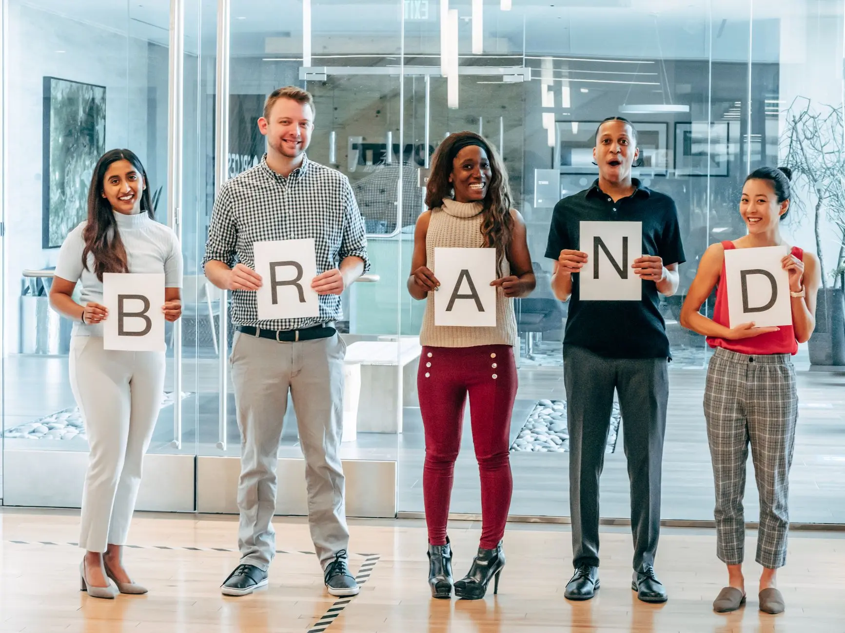 Happy coworkers holding up letters spelling BRAND