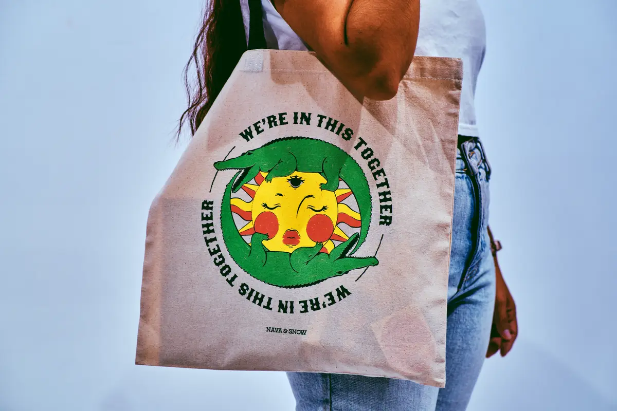 A person carrying a printed canvas tote bag with a colorful design