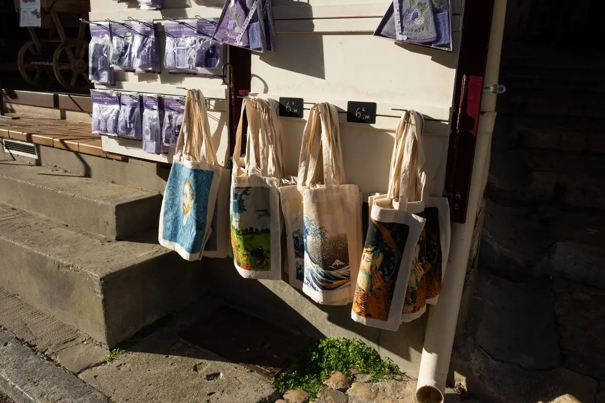 A display of printed canvas tote bags hanging outside a shop