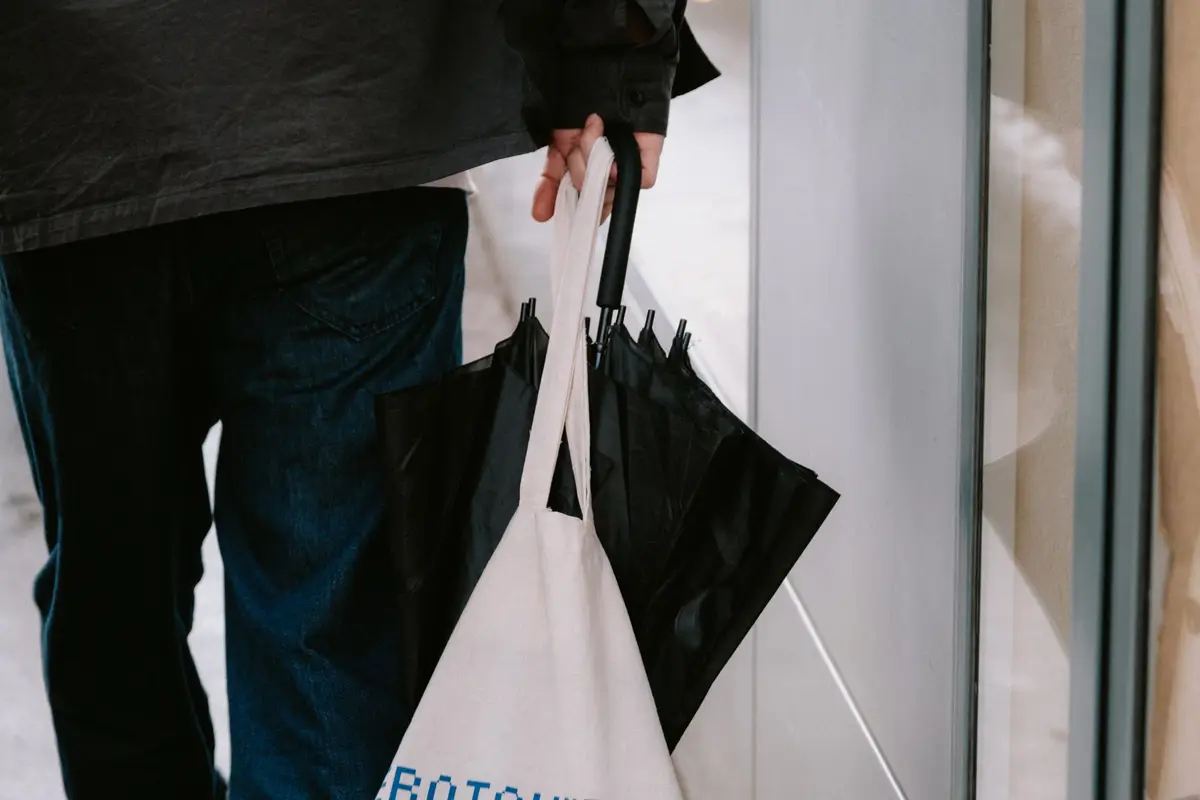 A person carrying a canvas tote bag while walking down a city sidewalk