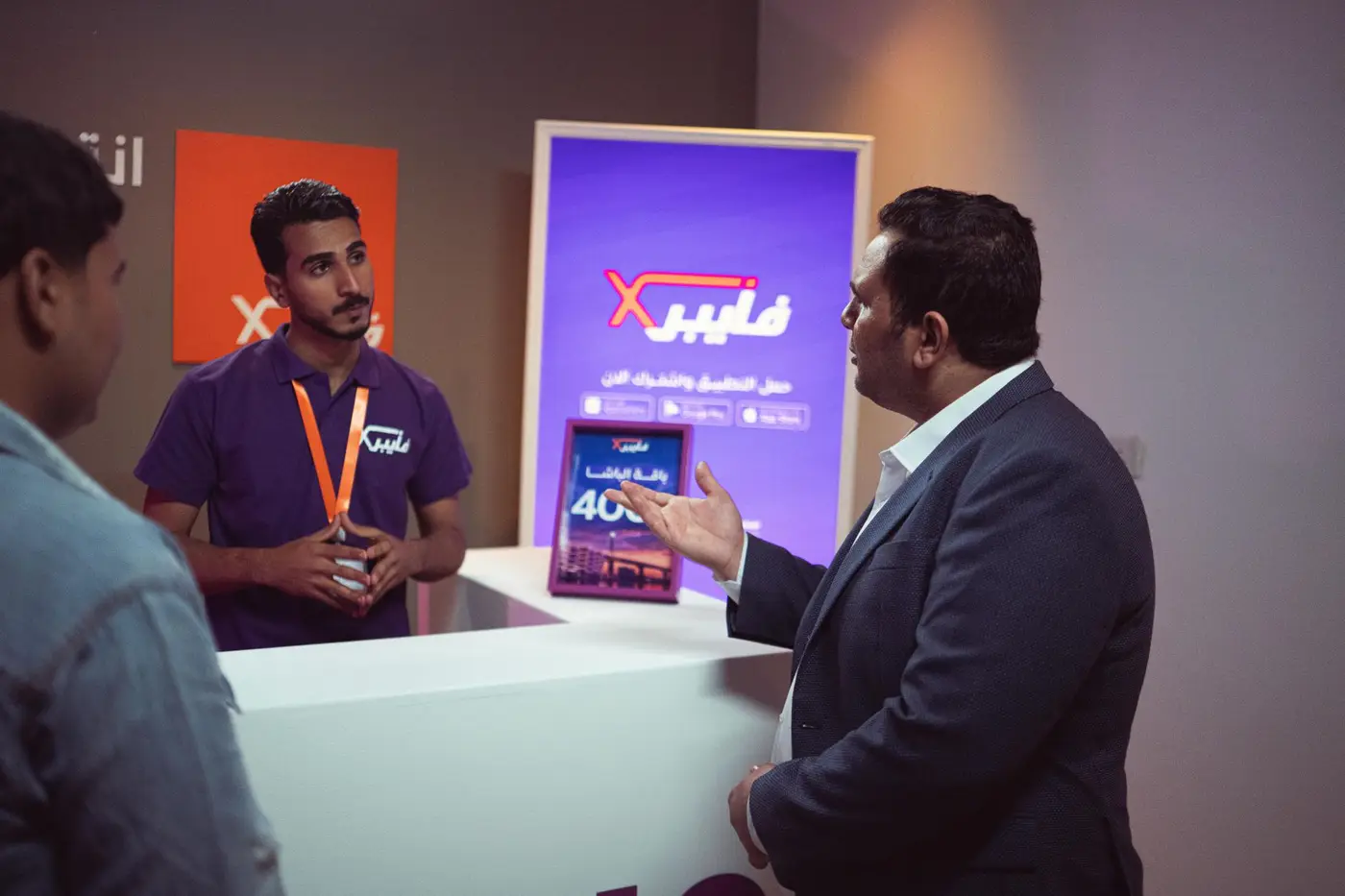 A person demonstrating a product to a visitor at an exhibition booth