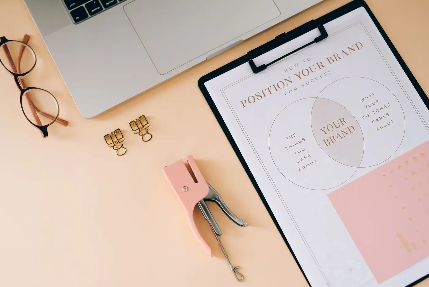 A desk flat lay with a notebook, glasses and brand planning materials