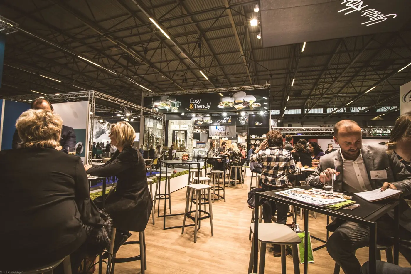 Professionals networking at tables inside a busy expo hall