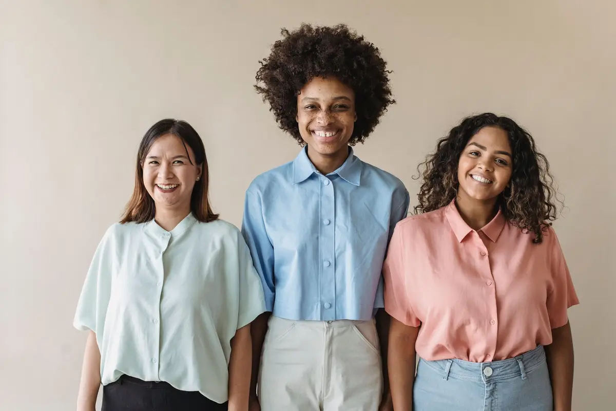 Three smiling coworkers standing together in a bright office