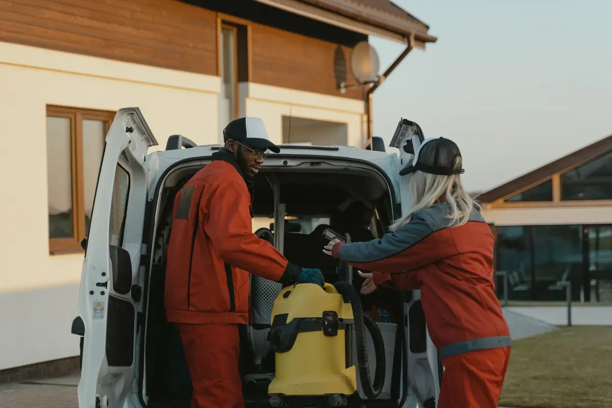 Two uniformed service techs loading equipment into a company van