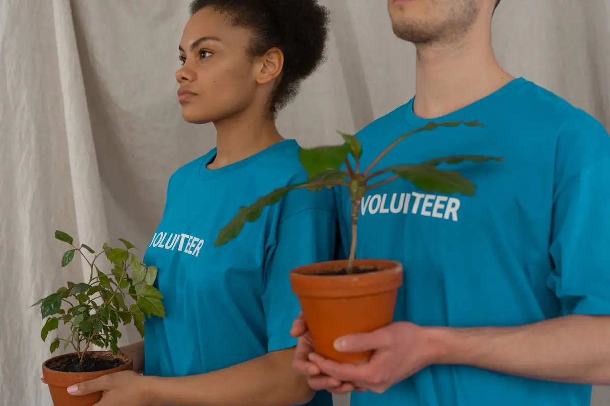 Volunteers in matching shirts holding potted plants at a community event