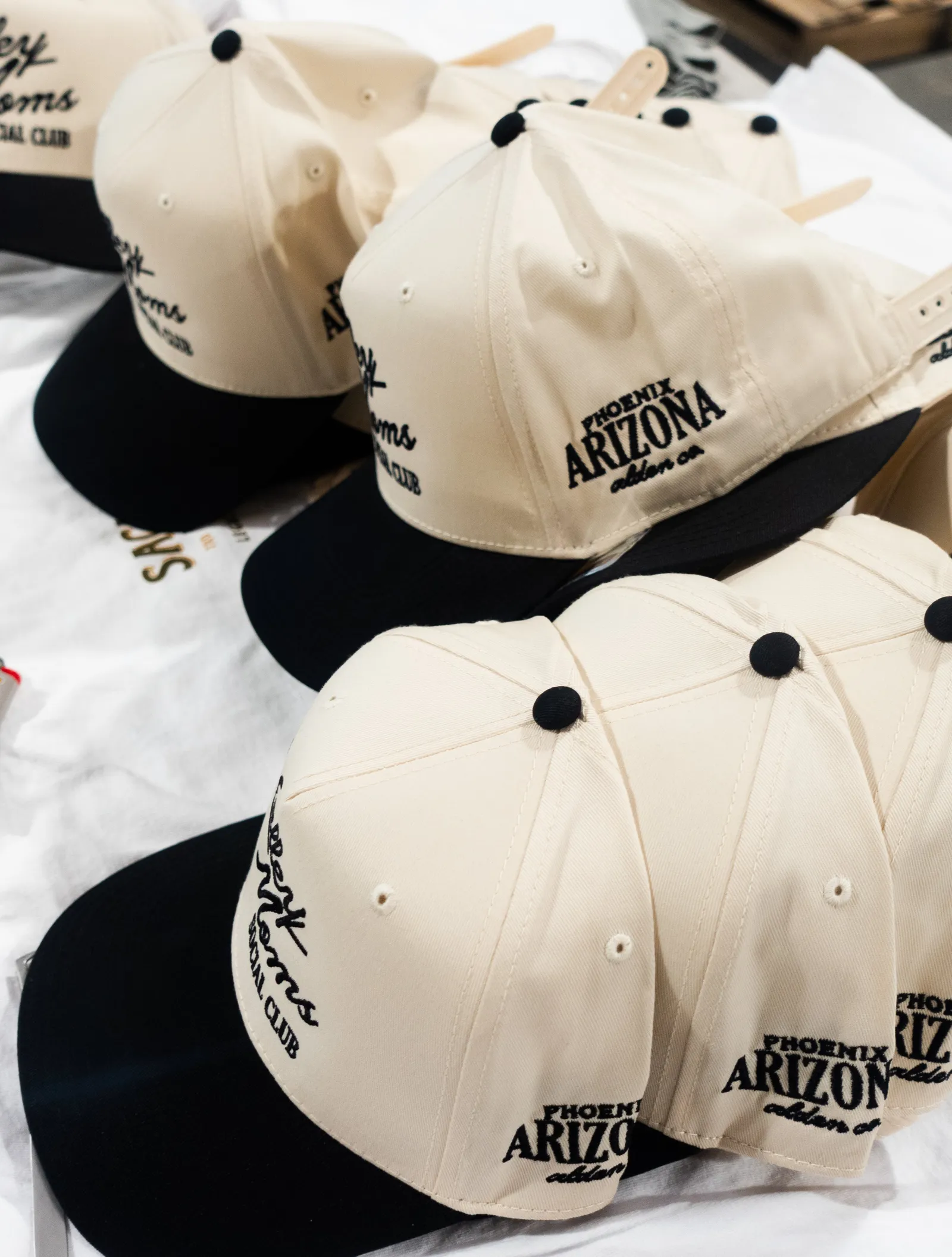 Custom embroidered caps stacked on a table in the Heart & Hook shop