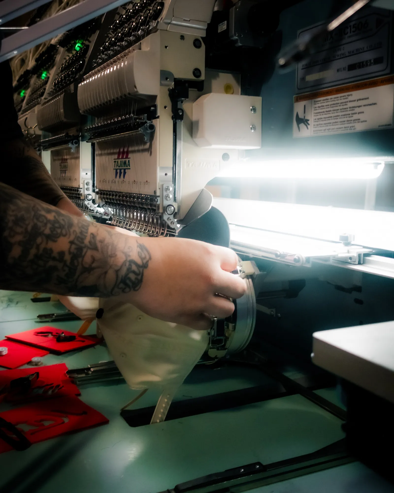 A shop worker hooping a garment on a commercial embroidery machine